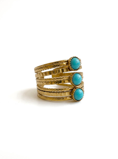 A multi-layered gold rings, each adorned with a round light blue turquoise stone, displayed on a clean white background.