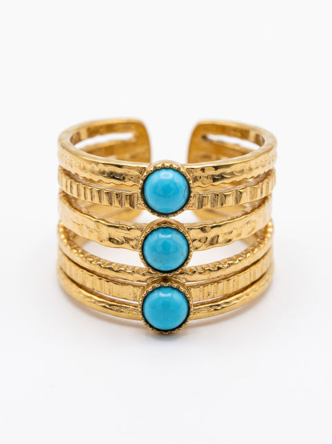 A gold-toned multi-band cuff ring featuring three round turquoise blue stone accents, photographed on a clean white background.