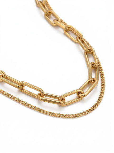 A gold-tone layered necklace featuring a paperclip chain and a finer curb chain, displayed on a clean white background.