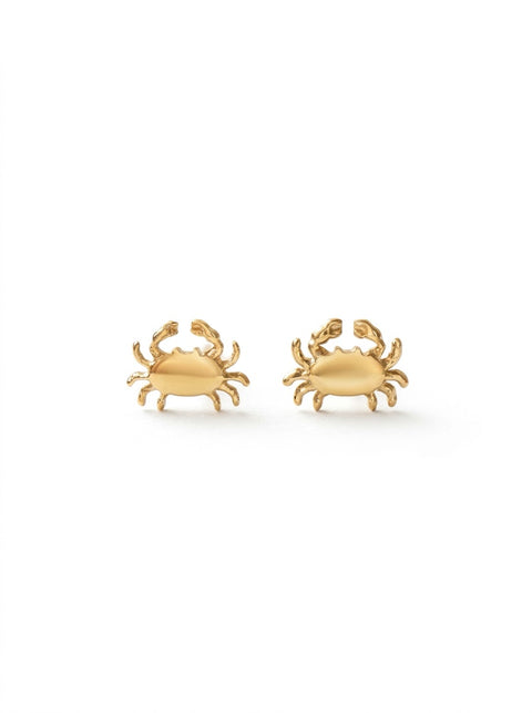 A small gold crab earrings sitting on a white background.